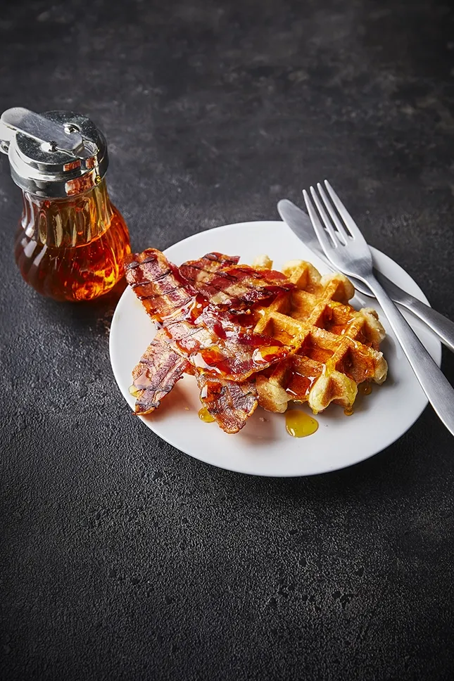 Waffles With Bacon And Maple Syrup on slate background